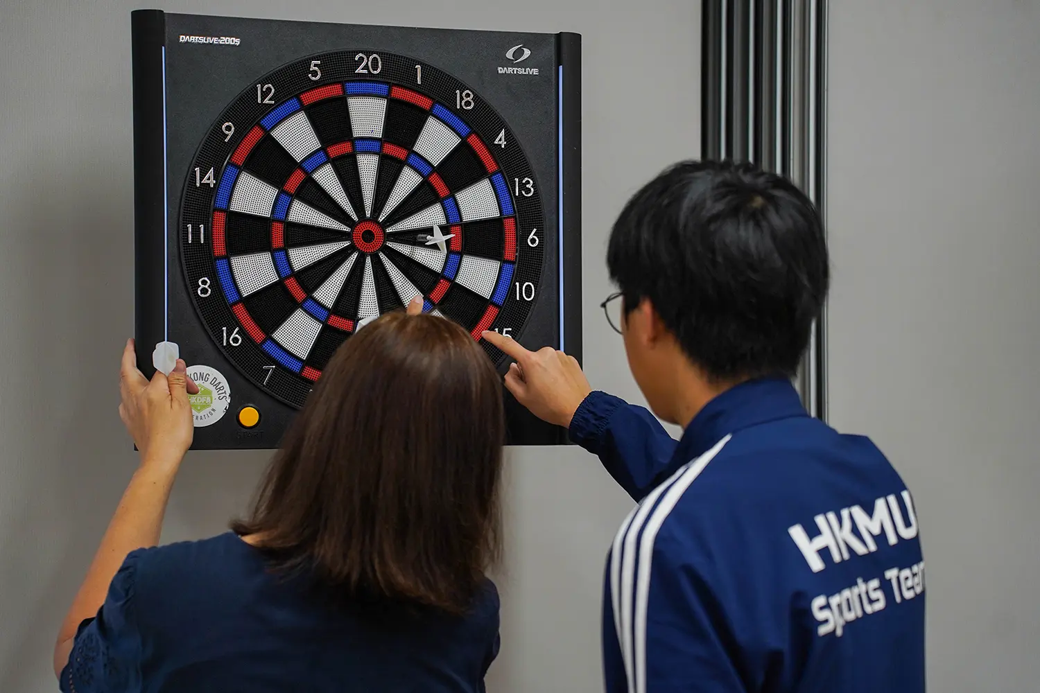 Student volunteers join hands with visually impaired athletes in a darts tournament to promote inclusion